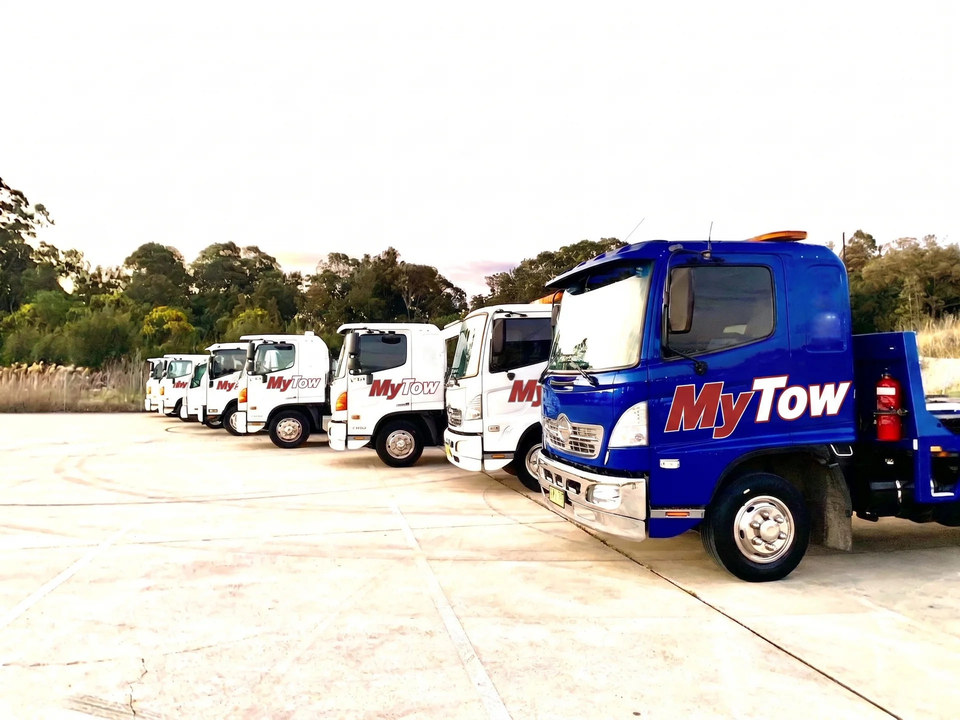 Row of MyTow tow trucks parked outdoors