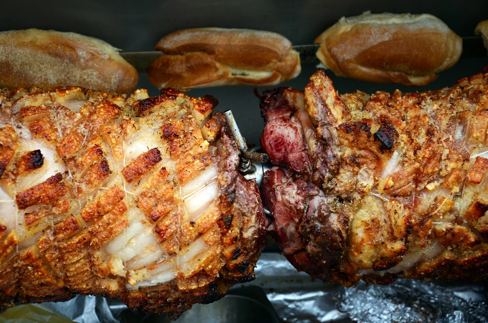 Rolled pork roasts with golden crackling turning on the spit